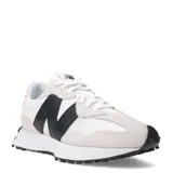 Championes urbanos New Balance modelo 327, con diseño inspirado en el running de los años 70. Presentan una combinación de paneles de gamuza en tono beige claro y malla blanca, con el logo 'N' sobredimensionado en color negro en el lateral. Incluyen una entresuela de espuma blanca y una suela exterior de goma negra con patrón tipo trail que se extiende hacia el talón.