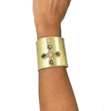 Brazalete dorado con diseño de cruz central adornada con piedras naturales rosas y verdes.