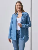 Camisa celeste de tencel con cuello con solapa, escote en V, abertura central con botones, bolsillo aplicado y ruedo desflecado.