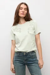 Remera de manga corta color crudo con apliques florales bordados tono sobre tono en el frente.