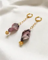 Par de caravanas colgantes con aro dorado, cadena dorada, pieza irregular de resina marmolada en tonos rosa y gris, y esfera dorada con incrustaciones de strass.