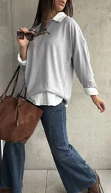 Sweater de punto color gris, de corte holgado y diseño de manga larga con costuras visibles en los hombros. Presenta cuello redondo y puños acanalados.