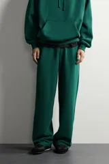 Pantalón jogger de corte relajado y pernera ancha, confeccionado en tejido de algodón con interior perchado. Cuenta con cintura elástica ajustable mediante cordón interior, bolsillos laterales y un bolsillo trasero de plastrón.