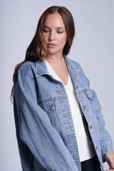 Campera clásica de jean celeste con cuello camisero, bolsillos frontales con solapa y cierre con botones metálicos. Presenta detalles de pequeños brillos blancos dispersos en la parte delantera y las mangas.