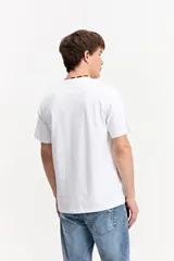 Remera de algodón color beige, de manga corta y cuello redondo, con logo estampado en el pecho en tono morado.