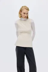 Top sin mangas de color beige confeccionado en punto roma, de corte entallado con costuras moldeadoras delanteras y traseras, cierre oculto en la espalda y detalle de peplum en la parte inferior.