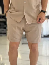 Bermuda tejida color beige con cintura elástica y cordón de ajuste interno.