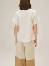 Blusa de lino color rosado, de corte recto y holgado, con cuello redondo y mangas cortas adornadas con volados.