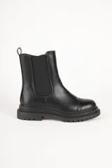 Bota Chelsea de cuero sintético color negro, con elástico lateral, puntera redondeada con detalle de perforaciones y suela track.