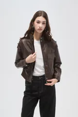 Campera de eco-cuero negro con cuello alto, cierre frontal, bolsillos con solapa en el pecho y puños y ruedo elásticos.