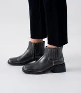 Bota corta de cuero vacuno con acabado desgastado, diseño de punta cuadrada y taco cuadrado de 4 cm. Cuenta con cierre lateral interno, elástico lateral externo y suela de caucho.