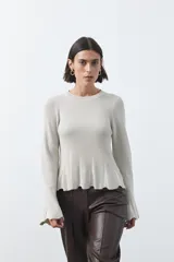 Top de tejido acanalado con sutil acabado metalizado, de silueta entallada con diseño peplum en la cintura y mangas largas levemente acampanadas.