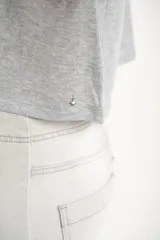 Remera gris de algodón con poliéster, corte crop, mangas cortas y bolsillo en el pecho.