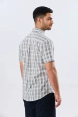 Camisa de manga corta confeccionada en mezcla de lino y algodón, con diseño a cuadros en tonos gris, blanco y azul. Presenta cuello camisero con botones y bolsillo ojal en el pecho con detalle bordado.