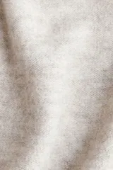 Saco largo de punto fino color beige, con lana en la trama, hombros caídos y ribete acanalado en nuca, puños y bajo. No tiene cierre.