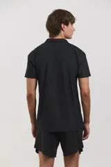 Chomba deportiva de manga corta, color negro, con cuello polo y cierre frontal de tres botones. Confeccionada en tejido técnico ultra liviano, fresco y respirable con alta elasticidad.