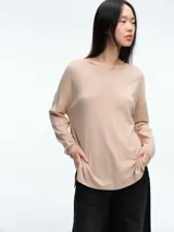 Sweater de punto amplio con sutiles micro lentejuelas integradas al tejido. Presenta cuello redondo relajado, hombros caídos y mangas largas con puños ajustados. Su diseño cuenta con un largo generoso y aberturas laterales en el ruedo.