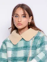 Tapado corto con diseño a cuadros en tonos violeta, rosa y blanco. Cuenta con interior de corderito color beige y cierre frontal con cremallera diagonal.