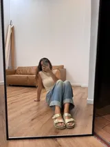 Sandalias bajas doradas con estampado de piel de cocodrilo, dos tiras anchas con hebillas doradas ajustables y plantilla de cuero.