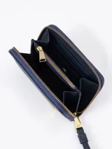 Billetera compacta de cuero vacuno color bordó, con cierre perimetral, correa de muñeca y aplique metálico dorado en forma de mariquita en el frente.