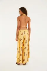 Mono largo amarillo con estampado de conchas, escote halter con lazo y corte holgado.