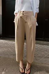 Pantalón de tiro bajo con pinzas delanteras, bolsillos frontales y bolsillos de plastrón con solapa en la parte trasera. Presenta una pernera ancha y bajo con botones a presión para ajuste.