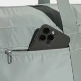 Bolso deportivo Adidas de diseño minimalista en color gris, con correas de hombro integradas y correa ajustable extraíble. Cuenta con un bolsillo frontal con cierre y logo de la marca estampado en tono sobre tono.