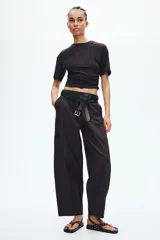 Pantalón cargo de corte holgado en color marrón, confeccionado en mezcla de algodón y nailon. Presenta cintura elástica de talle alto y perneras estilo globo con bolsillos tipo parche a los lados y costuras visibles en la parte delantera.