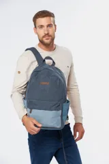 Mochila azul de lona tipo canvas con bolsillo frontal y logo de la marca en etiqueta de cuero.