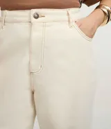 Pantalón femenino curve & plus size color beige, confeccionado en sarga de algodón certificado. Presenta un modelo recto, cierre delantero con botón y cremallera, bolsillos delanteros y traseros funcionales, y bajo con acabado deshilachado.