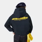 Hoodie oversize azul marino con capucha y texto estampado en la espalda en amarillo: "emestudios" y debajo "exclusive pieces selected with care".