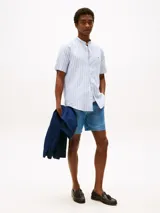 Camisa de manga corta Tommy Hilfiger con rayas verticales celestes y blancas, cuello mao, cierre con botones y logo bordado en el pecho.