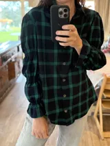 Camisa de manga larga con estampado de cuadros en tonos rojos, blancos y azules. Presenta un diseño con mangas abullonadas divididas por secciones elásticas y cierre frontal con botones.