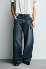 Jeans de denim de algodón, color azul oscuro con efecto lavado. Presentan un corte muy holgado (baggy fit) en toda la pierna y tiro medio. Tienen cinco bolsillos y cierre frontal con cremallera y botón.