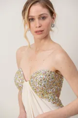 Vestido largo marfil de gasa, strapless, con bustier bordado en pedrería brillante y diseño drapeado en el frente.