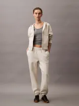 Buzo con capucha y cierre frontal completo, color beige jaspeado, confeccionado en suave fleece de mezcla de algodón y poliéster. Presenta bolsillos laterales y el logo Archive de Calvin Klein bordado en el pecho.