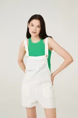 Enterito corto blanco con breteles anchos, escote recto con detalle de flecos y bolsillos delanteros.