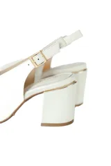 Zapato destalonado de cuero natural color off-white, con taco cuadrado alto, punta cuadrada y tira ajustable en el talón. Cuenta con una abertura en el empeine y detalle de ribete dorado en la parte superior del tacón.