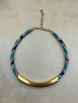 Collar de diseño minimalista con una pieza central curva de metal plateado mate y cordón trenzado con textura tipo piel de serpiente en tonos rosados y oscuros.