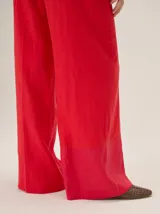 Pantalón sastrero de corte ancho, color beige con rayas verticales blancas y detalles de costuras pespunteadas.