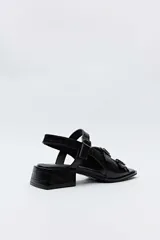 Sandalias de taco bajo cuadrado color negro con textura efecto cocodrilo, punta cuadrada y múltiples tiras cruzadas en el empeine con hebillas metálicas plateadas.
