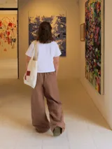 Pantalón de lino de corte holgado y tiro ajustable, con cintura elástica y cordón. Presenta bolsillos laterales y un bolsillo trasero.