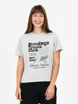 Remera gris melange de corte clásico y manga corta, con estampa frontal temática de tenis que incluye texto y una raqueta.