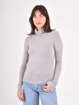 Polera de tejido de punto fino, con cuello alto doblado y mangas largas. Presenta un diseño ajustado al cuerpo con terminaciones acanaladas en puños y ruedo.