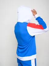 Canguro de felpa Umbro del Club Nacional de Football, con diseño tricolor en rojo, azul y blanco. Presenta capucha con cordones ajustables, bolsillo tipo canguro frontal, logo de la marca y escudo del club bordados en el pecho.
