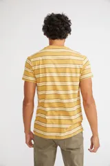 Remera de hombre de manga corta y cuello redondo, con diseño de rayas horizontales en tonos mostaza, blanco y negro. Presenta un ajuste regular y logo pequeño estampado en el pecho.