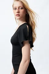 Vestido negro de un solo hombro con escote asimétrico y manga volada con tajo. El tejido es muy elástico y ajustado al cuerpo.