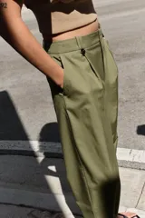 Pantalón de tiro alto con corte recto, bolsillos delanteros y detalle de pinzas con botones en la cintura. Cuenta con cierre frontal de cremallera y gancho metálico.