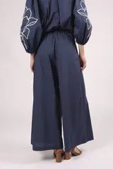 Pantalon de corte ancho y tiro alto, color azul marino, con bordados florales en color crema en la parte inferior de las piernas.
