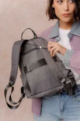Mochila compacta de color beige, con compartimento principal con cierre, bolsillos laterales y bolsillo frontal con cierre oculto. Cuenta con correas regulables y acolchonadas y asa superior.